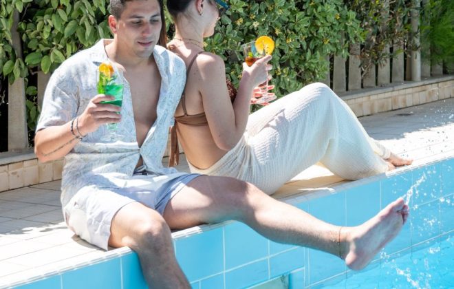 Coppia seduta a bordo piscina con un drink durante una bellissima giornata