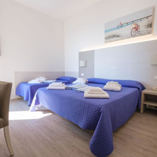 Camera SUPERIOR Luminosa ed elegante camera con letto matrimoniale e singolo con copriletto blu e teli da bagno Camera SUPERIOR Luminosa ed elegante camera con letto matrimoniale e singolo con copriletto blu e teli da bagno