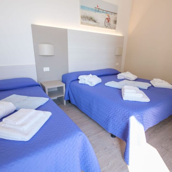 Camera SUPERIOR Luminosa ed elegante camera con letto matrimoniale e singolo con copriletto blu e teli da bagno Camera SUPERIOR Luminosa ed elegante camera con letto matrimoniale e singolo con copriletto blu e teli da bagno