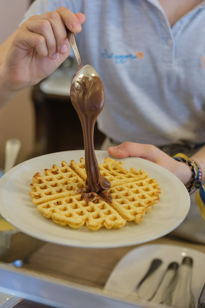 addetto al buffet mette la nutella su un waffle appena preparato