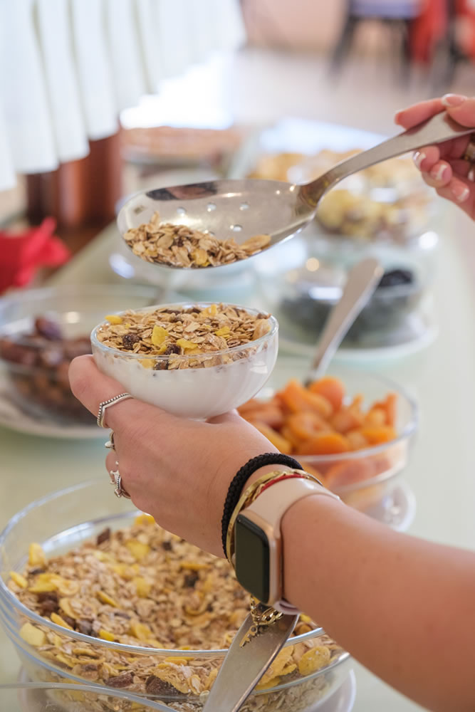 Una cliente al buffet di colazione si prepara una tazza di yogurt e muesli