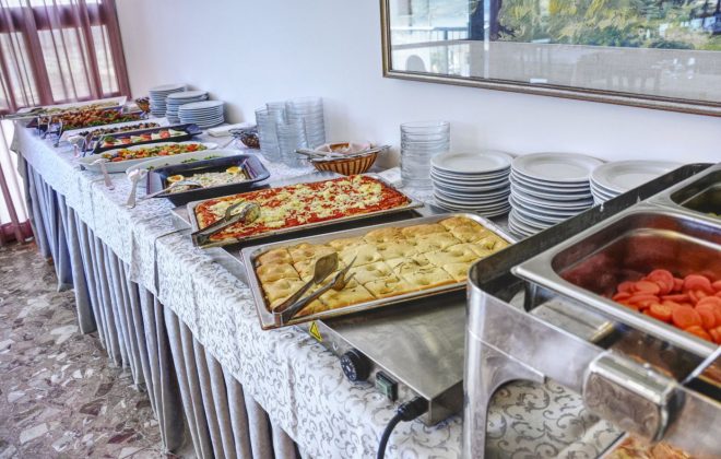 Ricco buffet con teglie di pizza e spianata al rosmarino