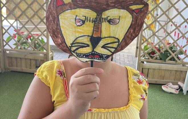Bambina si copre il viso con la sua maschera da leone