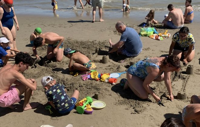 Gara di castelli di sabbia con adulti e bambini in riva al mare