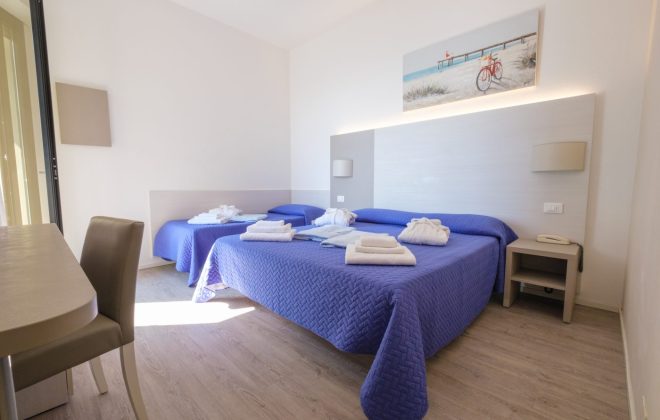 Camera SUPERIOR Luminosa ed elegante camera con letto matrimoniale e letto singolo con copriletto blu e teli da bagno e accappatoi