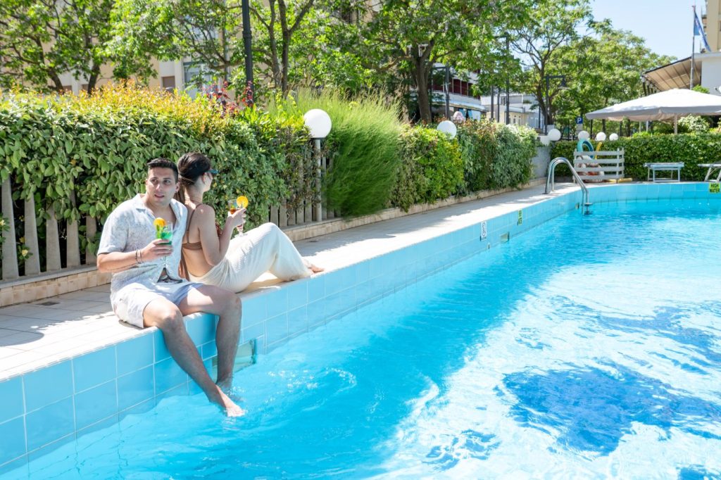 Coppia seduta a bordo piscina con un drink durante una bellissima giornata