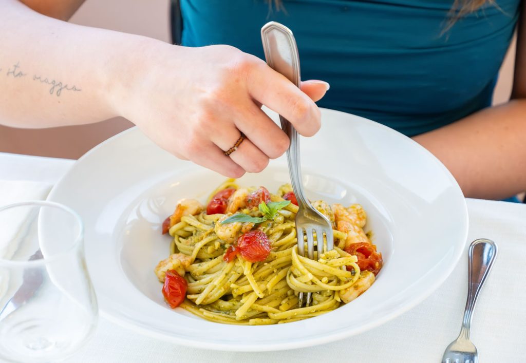 piatto di linguine al pesto, pomodorini e gamberi